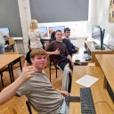 Grupa uczniów siedzi przy komputerach w pracowni.